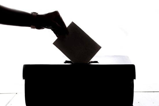 Hand placing card into ballot box 