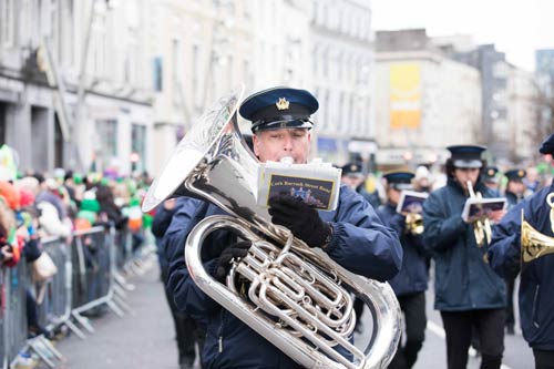 Person in blue uniform marching with large silver instrument