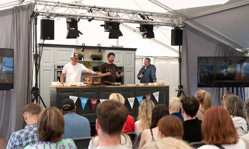 People on stage at cooking demo in  marquee