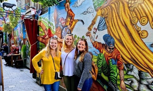 Three ladies enjoying Cork Culinary Tour with colourful mural in the background