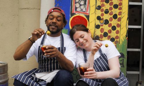 a man and a woman sitting on a step enjoying a drink with olives
