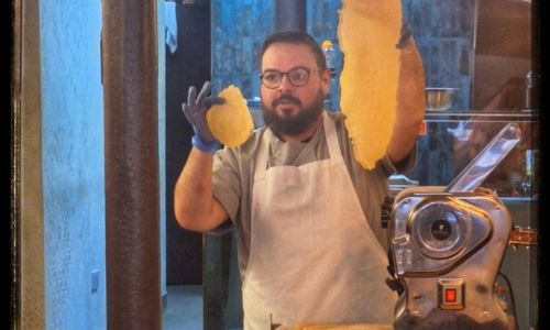 Man holding up two pieces of dough showing how to make pasta