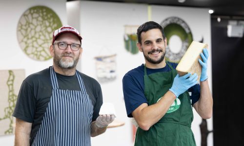 Two cheese producers holding their cheese