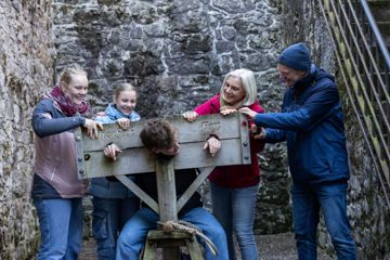 Family Trying Out The Stocks At Elizabeth Fort
