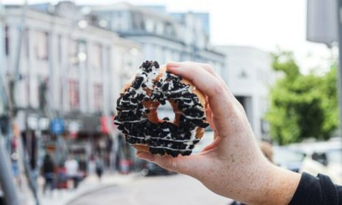 A person holds a donut up with city main street as backdrop