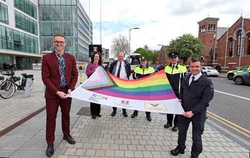 Photo showing 6 people standing on the street outside Cork City Council holding the Proigress Pride flag between them