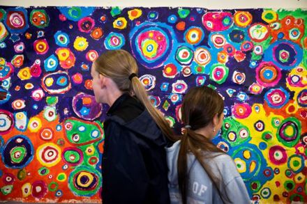 Two girls looking at a large swirling painting at the Roam exhibition in Mayfield Library