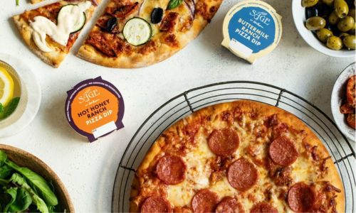 pizzas and sauces with bowl of olives and other condiments