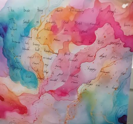 Child's marbled painting with handwritten message: "The best thing about Knocknaheeny is the people.  The smell of freshly cut grass reminds me of home. When I step outside I see a  park. If Knocknaheeny was a person it would be Billy Murphy because he's funny. I would tell Knocknaheeny pick up your dogs poo. During Covid I missed my friends. When I roam my area I feel happy because I am going to the shop to get  sweets. I wish people could see more dogs on a leash."