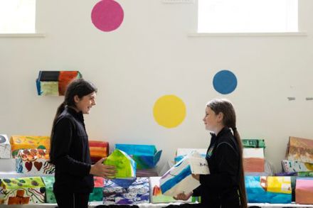Roam exhibition in Knocknaheeny Youth Project - two primary school girls holding painted cardboard houses