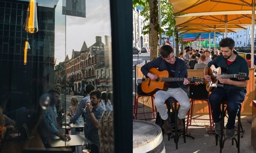 Two musicians playing guitar and a man looking out the window of cafe